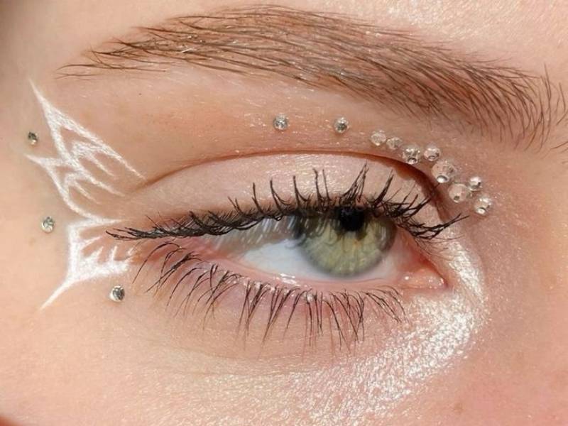 اجرای ترند آرایشی پاییز ۱۴۰۴ با استفاده از یک مدل خط چشم گرافیکی سفید، نمونهای از میکاپ خلاقانه برای صورت پاییزی.